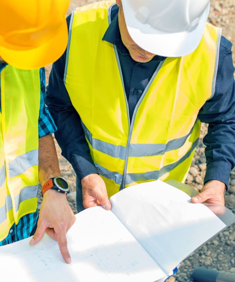 Bauarbeiter mit Helm schauen sich einen Plan an