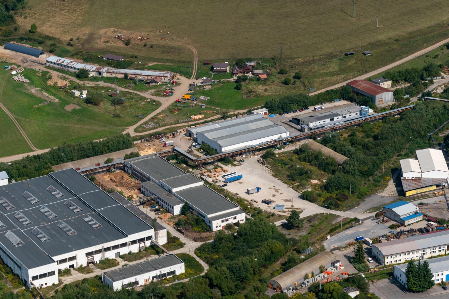 Vogelperspektive eines Industriestandortes mit mehreren Hallen und Ländereien drum herum
