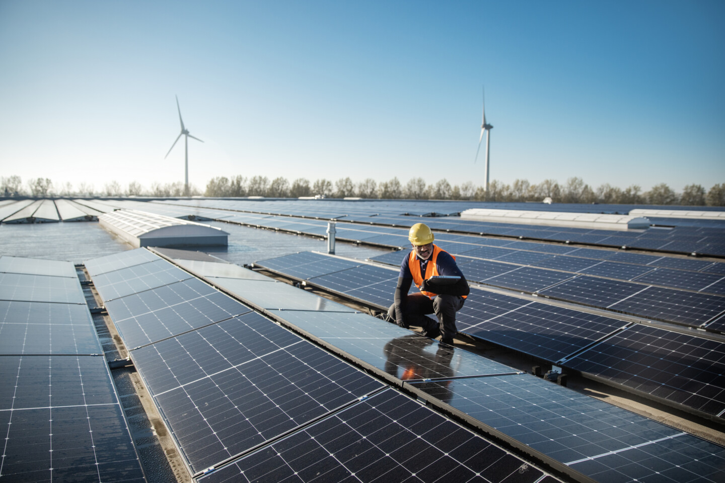 A black solar panel engineer working on a roof of panels on a sunny day in the Netherlands